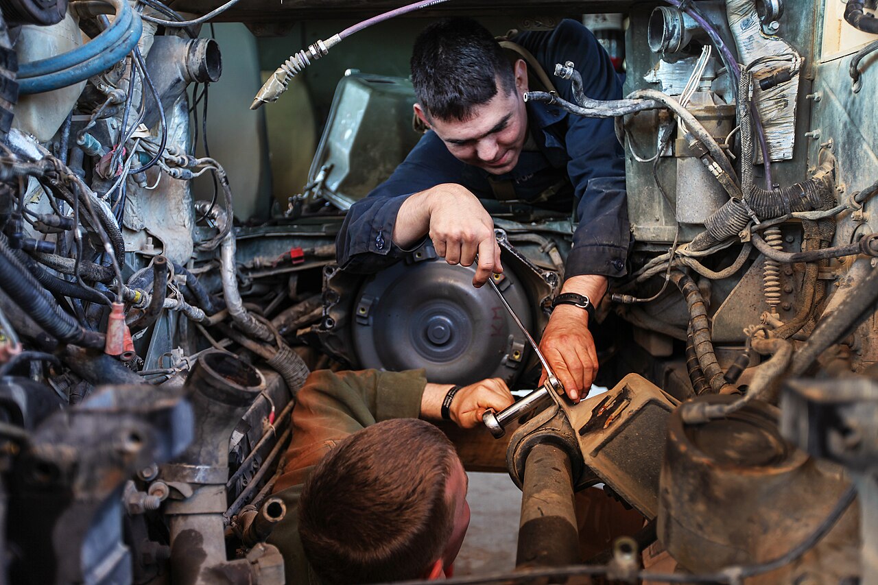 Technician working on a vehicle motor and wiring